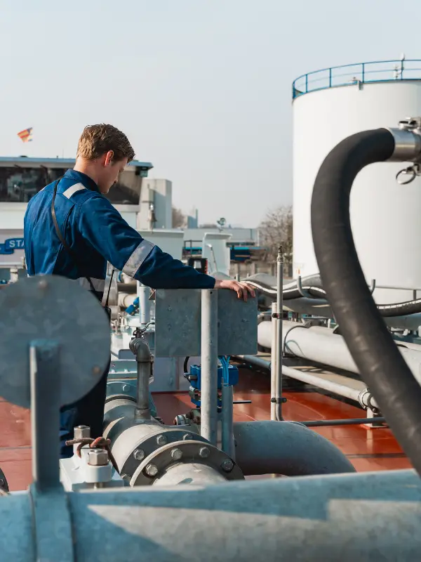 Medewerker van A. de Groot tussen de leidingen en installaties op het dek van een binnenvaartschip.
